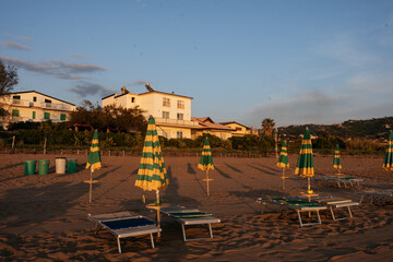 Sunset at Seashore with some buildings and umbrellas with stripes