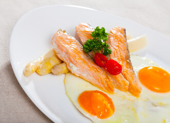 Delicious grilled salmon with eggs, tomatoes, asparagus and parsley. High quality photo