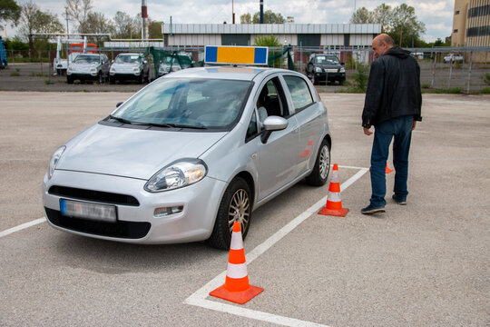 Beautiful Teenager With Instructor Learning How To Drive And Park Car Between Cones.