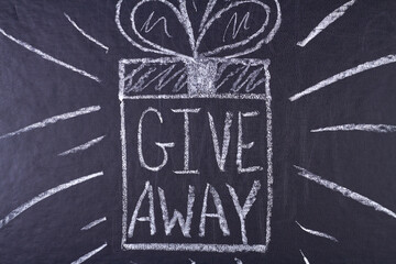 Give away handwritten inscription with white chalk on black chalkboard. Promotion concept.