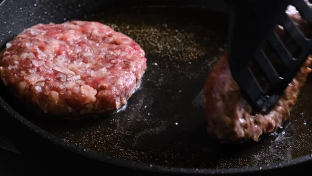 Overturn meat burgers patty in the frying pan. Preparation food. 4k video