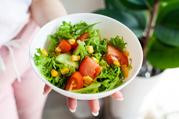 Bowl green healthy tasty eco salad in hand woman on light kitchen