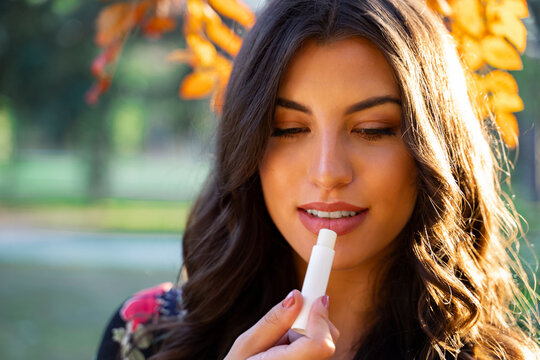 Closeup Shot, Beautiful Young Woman Putting On Lip Balm In The Park