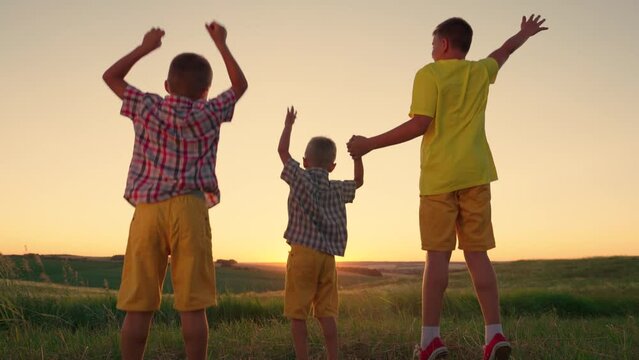 Happy children play, jump at sunset in park, Teamwork. Happy family. Boys friends have fun together dream. Childrens outdoor games. Child boy run in sun with brothers, family team, group of children