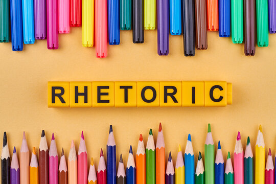 Flat lay composition with colorful pencils and word rhetoric written on yellow cubes. Education concept.
