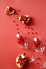 Glasses with pomegranate on red background. Pomegranate wine concept. Flat lay, top view.