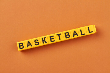 The word basketball written on yellow cubes against color background. Flat lay minimal.