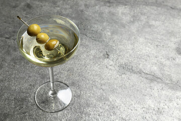 Martini cocktail with olives on grey table. Space for text
