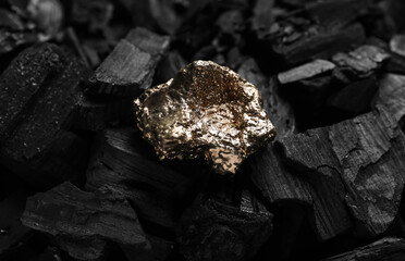 Shiny gold nugget on coals, closeup view