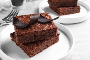 Delicious chocolate brownies served on white wooden table, closeup