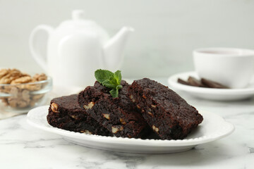 Delicious brownies with nuts and mint on white marble table. Space for text