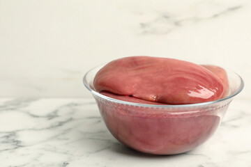 Bowl with fresh raw pork kidneys on white marble table, space for text