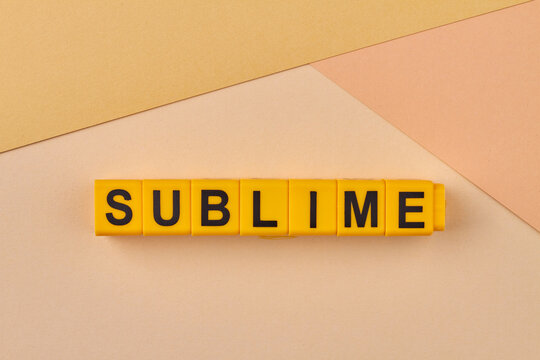Word sublime written on yellow blocks against color background. Persons attitude or behaviour concept.