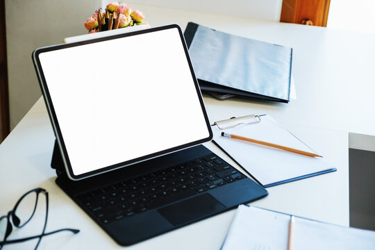 A white screen tablet computer placed on the desk at work. Can put text or media in the area on the white screen.