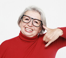 Senior happy woman wearing red sweater and glasses is making a call me gesture