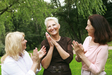 Happy retired women meet in the park. Two women friends in the park congratulate the third woman.