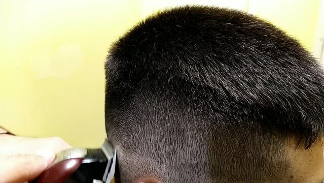 young man getting a haircut with a machine in a barbershop