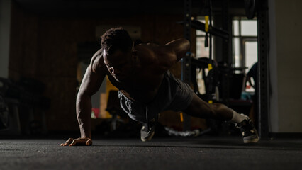 African american man doing one arm push ups in the gym. 