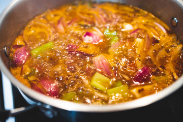 healthy plant-based food, vegan turkish güveç hot pot with eggplant celeri and potaotes in spicy broth with mixed herbs cooking on the stove