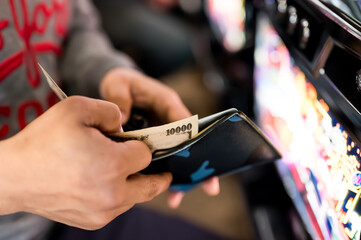 パチンコ屋で財布から1万円札を投資する様子