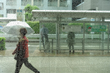 傘を差し、歩く女性。赤いレインコート、東京