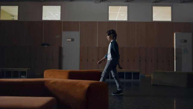 Pupil boy walking empty hallway alone. Bored teen schoolboy skipping classes.