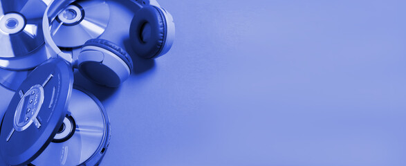 Personal compact portable CD player disks headphones blue neon background, Top view