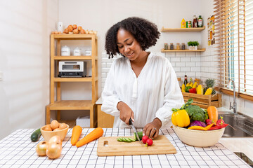 African American housewife is chopping organic cucumber to prepare simple and easy southern style...