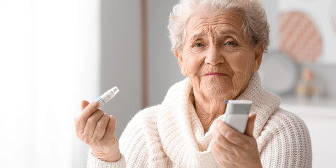 Elderly woman with glucometer and lancet pen at home. Diabetes concept