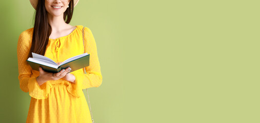 Beautiful young woman reading book on color background with space for text