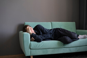 Obraz premium young guy lying and sleeping on the sofa at home in the afternoon
