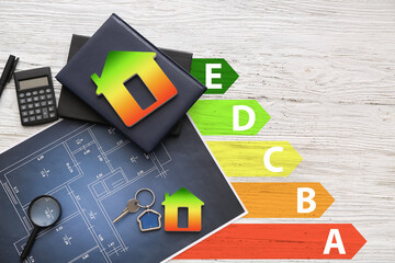 Drawings with figures of houses, key, calculator and magnifier with notebooks on light wooden background. Concept of energy efficiency