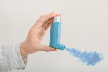 Female hand with inhaler on light background