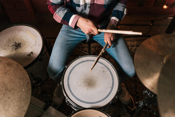 From above of crop anonymous musician with drumsticks playing on drum set during live musical performance