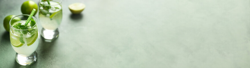 Glasses of fresh mojito on light color background with space for text