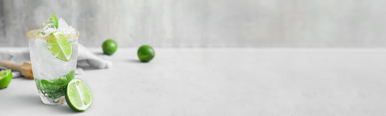 Glass of fresh mojito on light background with space for text