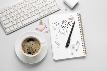 Notebook with blank to-do list, computer keyboard, coffee and stationery on light background