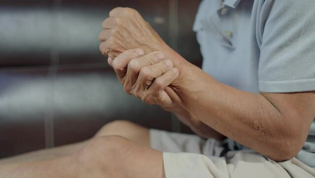 Healthcare and health problem. Asian Older man suffering from wrist pain. Health problem retired asian old man hands touching massage palm wrist while Relieve pain. Geriatric disease. B roll scene 4k.