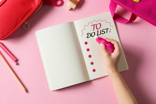 Child's hand and notebook with blank to-do list on pink background