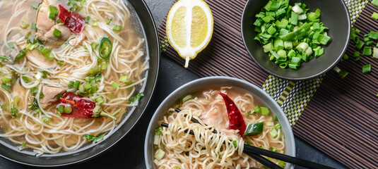Bowls of tasty Chinese soup on dark background, top view