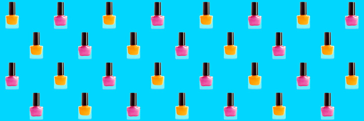 Many bottles of nail polishes on light blue background. Pattern for design