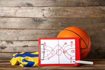 Clipboard with drawn scheme of basketball game, uniform and marker on dark wooden background