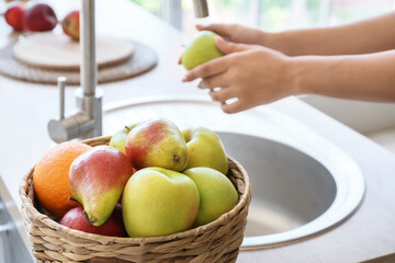 Wicker basket with different fruits on counter in kitchen, closeup