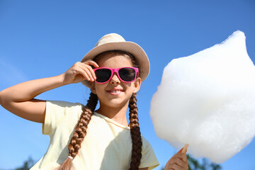 Cute little girl with cotton candy outdoors
