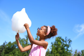 Little African-American girl with cotton candy outdoors