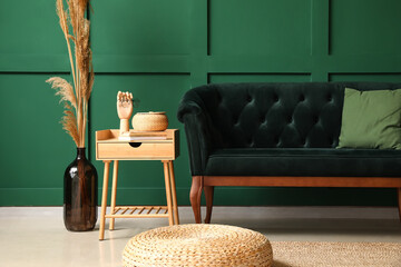Stylish sofa, pouf and table near green wall