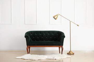 Stylish sofa and modern lamp near light wall