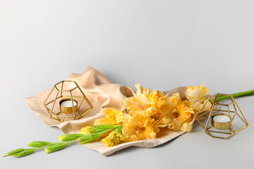 Composition with beautiful gladiolus flowers and candles on light background