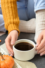 Woman drinking tasty pumpkin coffee on floor in room