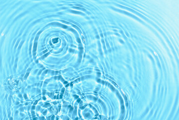 Naklejka na ściany i meble Texture of water with ripples on blue background, closeup